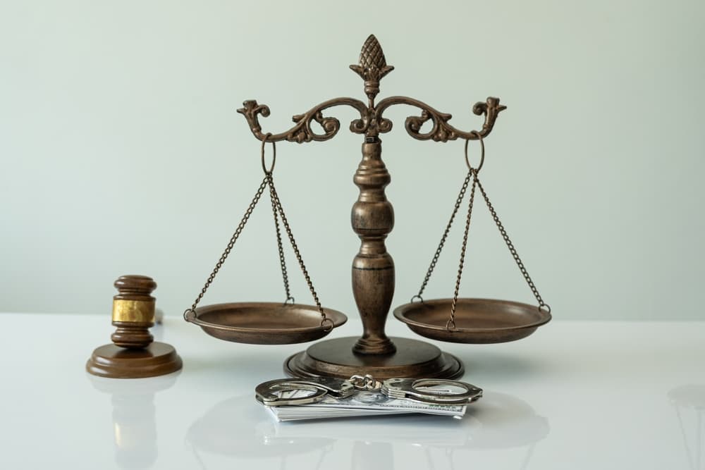 Handcuffs and dollars, scales of justice and judge's hammer on table