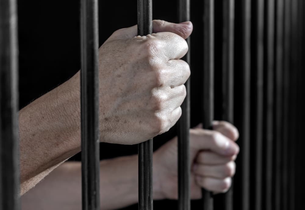 Prisoner's hands gripping the bars of a cell in jail for cocaine case