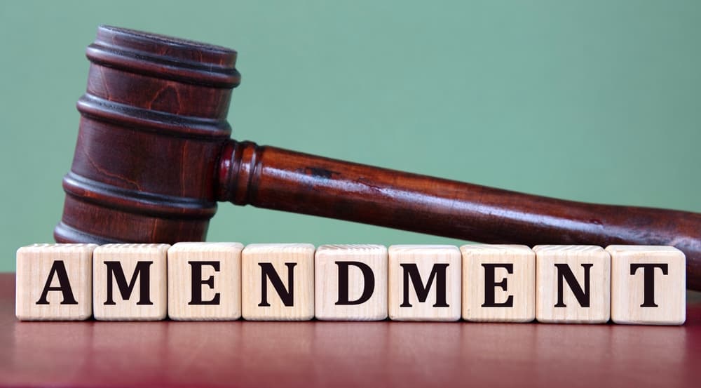 AMENDMENT spelled out on wooden blocks with a judge's gavel in the background, symbolizing a legal information concept.