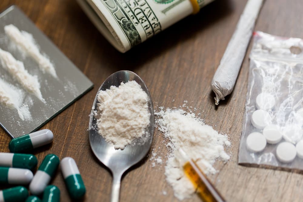 Drug use, crime, and addiction concept: close-up of drugs with money, a spoon, and a syringe.