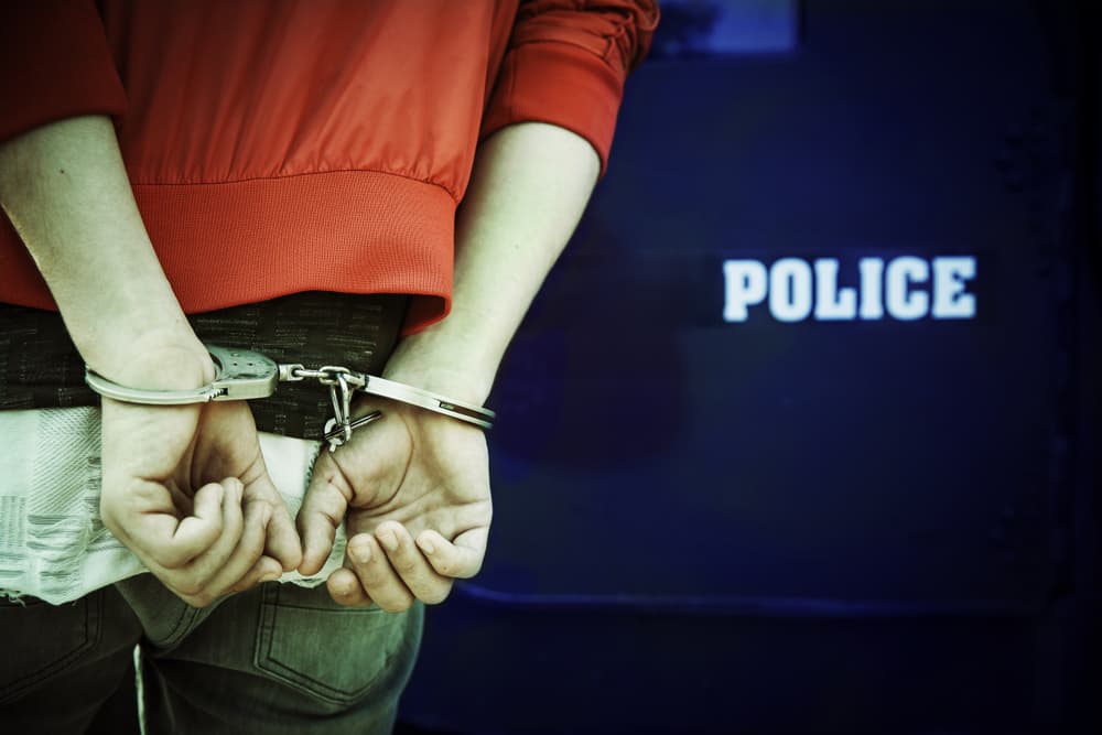 A man being detained and handcuffed by police officers. Law enforcement, arrest, and criminal justice concept.